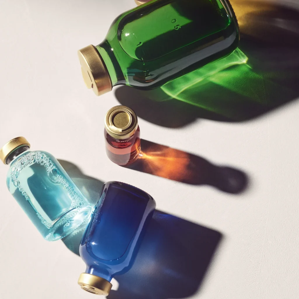 Serum bottles in green, amber and blue on a white surface